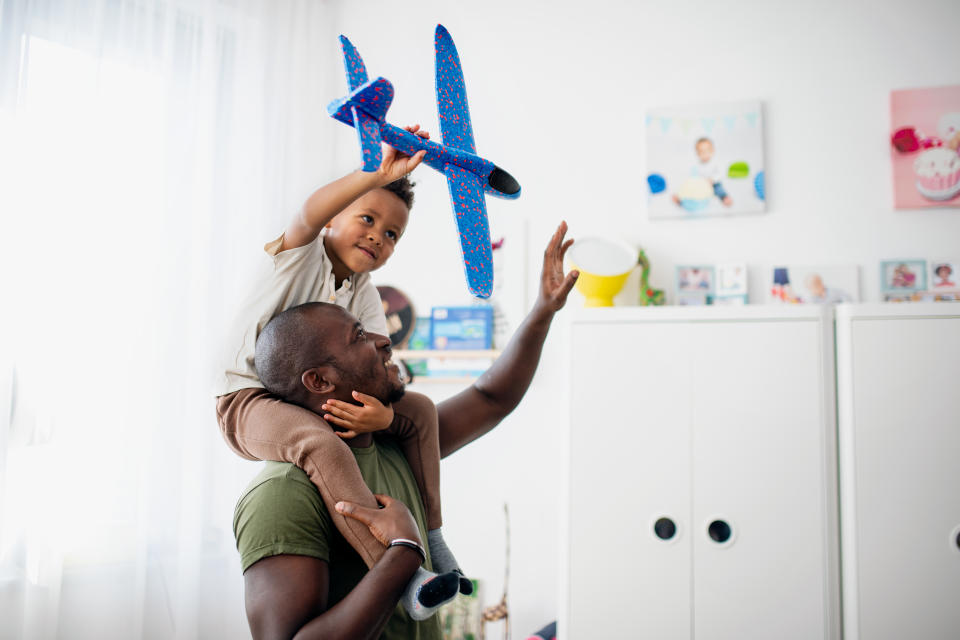 A father with his son on his shoulders holding a toy airplane