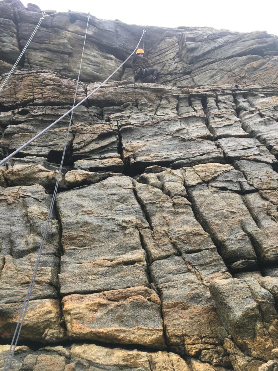 The author rappelling down an outdoor rock wall.