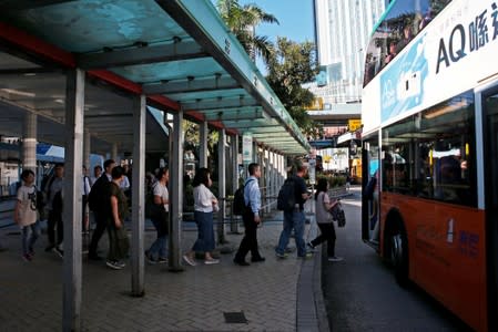 Passengers queue to ride a bus after a service delay in Cross Harbour Tunnel in Hong Kong, China