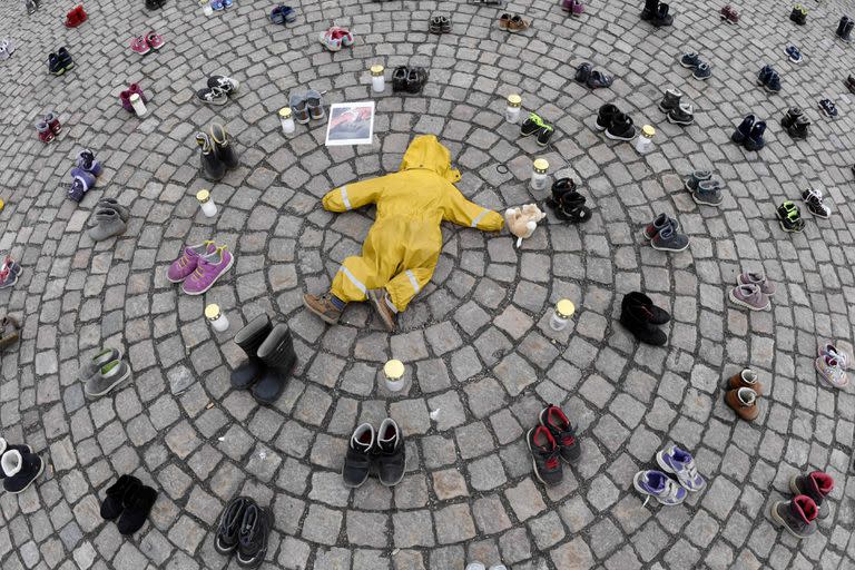TOPSHOT - Velas, ropa y zapatos de niños se ven durante una manifestación organizada por la Asociación Ucraniana en Finlandia, para honrar la memoria de los niños asesinados en Mariupol, Ucrania, en Helsinki, el 10 de abril de 2022. (Foto de Jussi Nukari / Lehtikuva / AFP) / Finlandia OUT