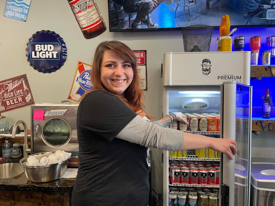 Rachelle Coke takes a break from making hot towels to stock the beer cabinet with lager at Tune Up, The Manly Salon at 6734 Malone Creek Drive Friday, Jan. 28, 2022.