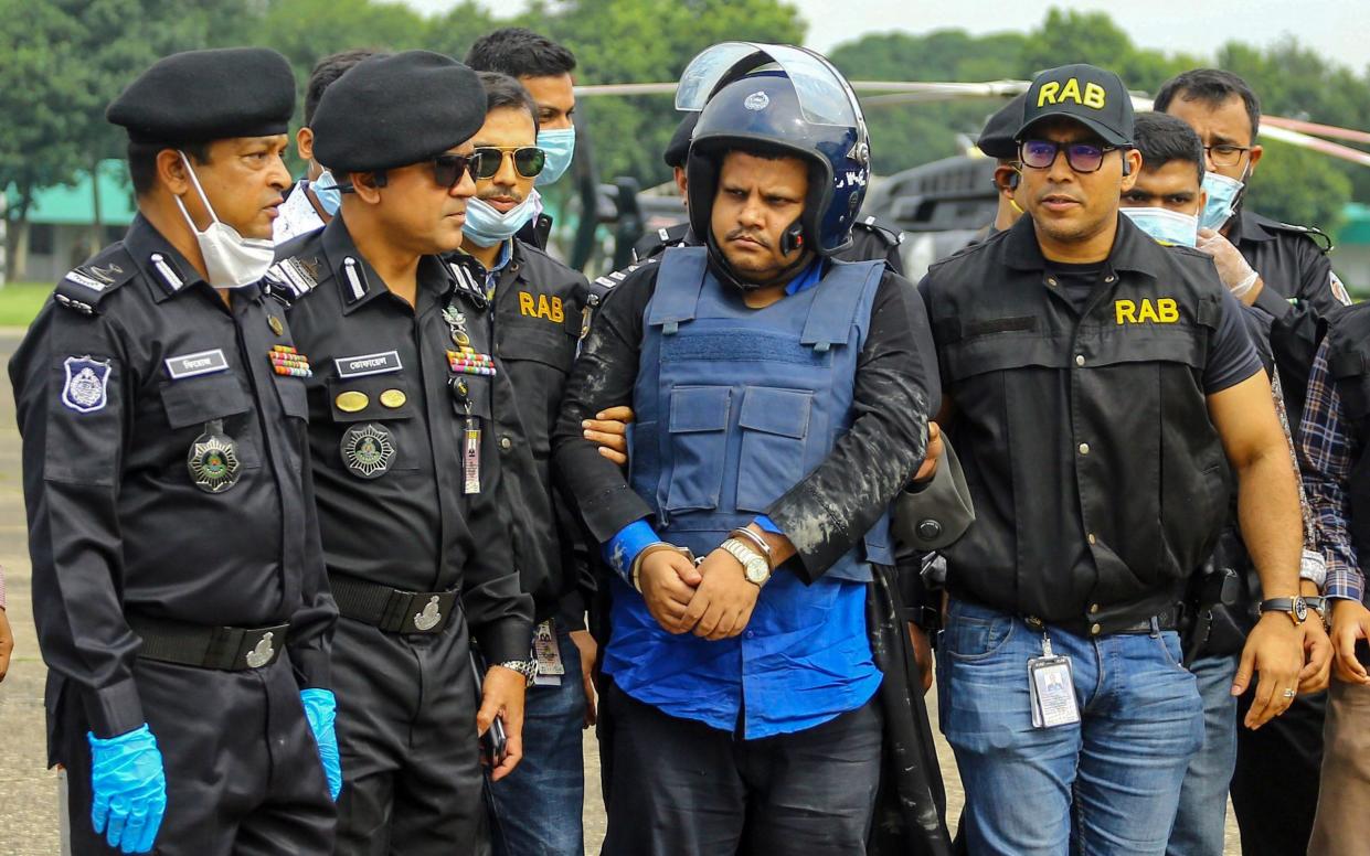 Rapid Action Battalion personnel escort Mohammad Shahed, centre - who is accused of distributing fake coronavirus certificates - following his arrest in Dhaka - AFP