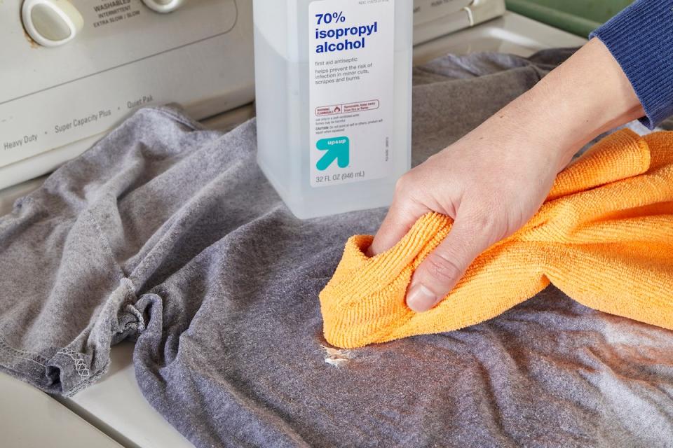 Woman blots a caulk stain on shirt with rubbing alcohol.