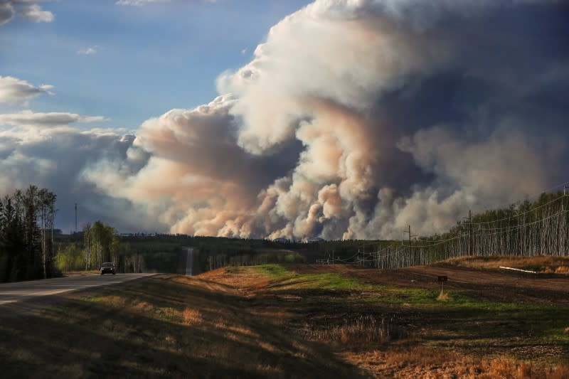 Smoke billows from the Fort McMurray wildfires as a truck drives down the highway in Kinosis, Alberta, Canada, May 5, 2016. REUTERS/Mark Blinch