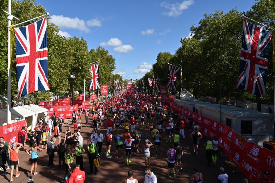 Runners relax on the Mall after finishing the 2021 London Marathon (AFP)