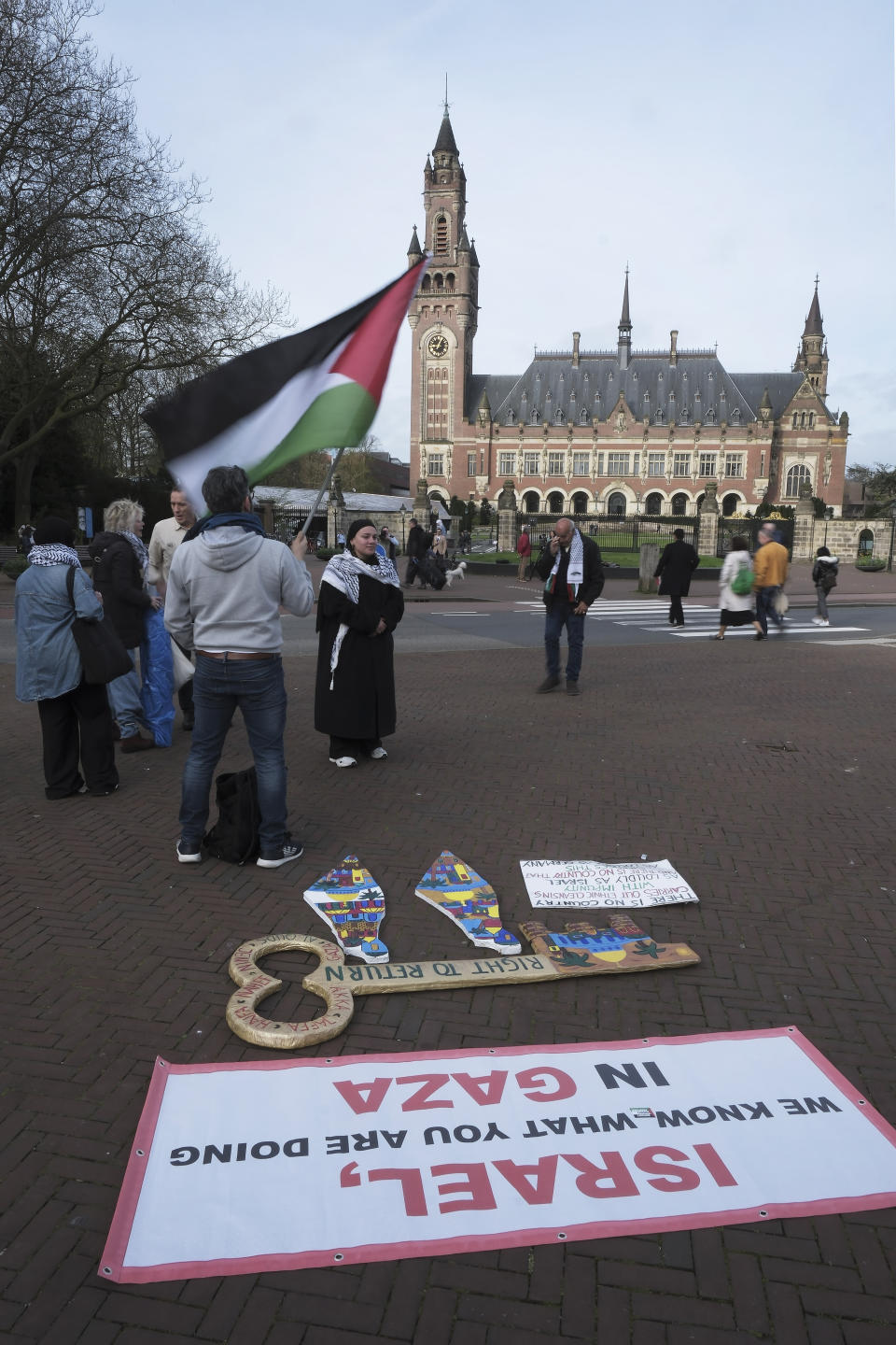 A pro-Palestinian activist works on a protest poster near the International Court of Justice, or World Court, in The Hague, Netherlands, Monday, April 8, 2024, prior to the start of a two days hearing in a case brought by Nicaragua accusing Germany of breaching the genocide convention by providing arms and support to Israel. (AP Photo/Patrick Post)