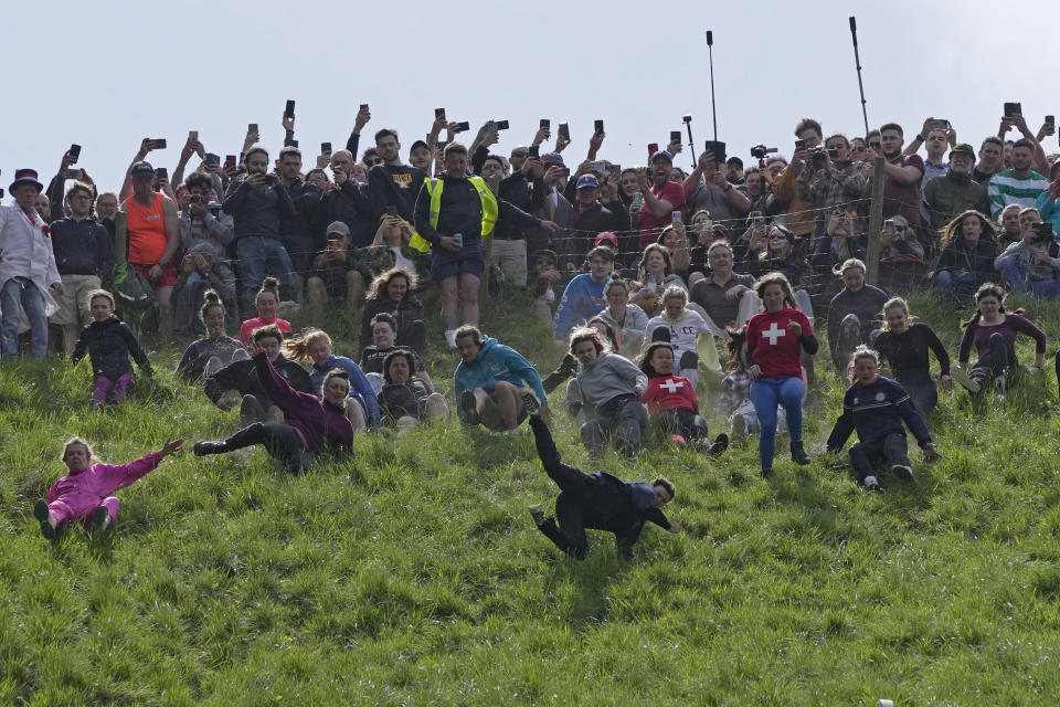 Participants compete in the women's downhill race during the Cheese Rolling contest at Cooper's Hill in Brockworth, Gloucestershire, Monday May 29, 2023. The Cooper's Hill Cheese-Rolling and Wake is an annual event where participants race down the 200-yard (180 m) long hill chasing a wheel of double gloucester cheese. (AP Photo/Kin Cheung)