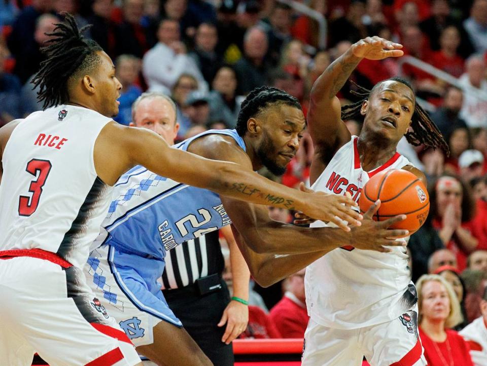 North Carolina’s Jae’Lyn Withers looks to pass around pressure from N.C. State’s MJ Rice and DJ Horne during the first half of the Wolfpack’s game at PNC Arena on Wednesday, Jan. 10, 2024, in Raleigh, N.C.