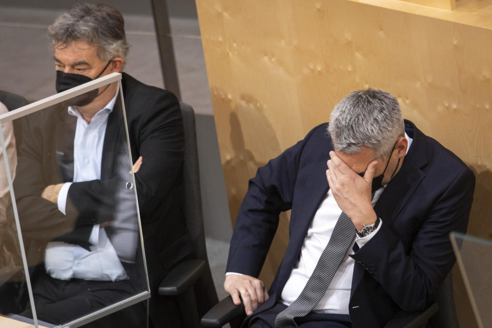 Austrian Vice Chancellor Werner Kogler, left, next to Austrian Chancellor Karl Nehammer during a parliamentary session where the compulsory COVID-19 vaccination is decided in Vienna, Austria, Thursday, Jan. 20, 2022. (AP Photo/Lisa Leutner)