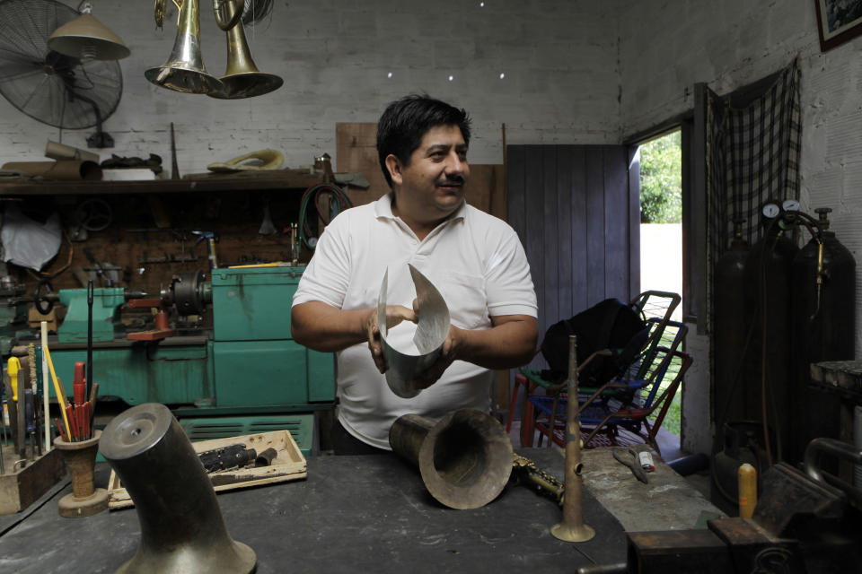 In this Dec. 8, 2012 photo, Tito Romero demonstrates how he makes a trumpet with recycled metal in his workshop at his home in Capiata, Paraguay. Romero was repairing damaged trumpets in a shop outside Asuncion until Favio Chavez, the creator of "The Orchestra of Instruments Recycled From Cateura," asked him to turn galvanized pipe and other pieces of metal into flutes, clarinets and saxophones for his students. (AP Photo/Jorge Saenz)