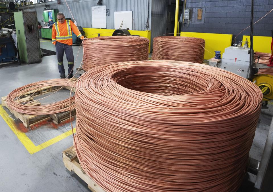 A worker looks at a coil at Nexans, one of the world's largest wire and cable manufacturers, Friday, April 12, 2024, near Montreal.  The company is increasingly mixing copper scrap into its products.  (Ryan Remiorz/The Canadian Press via AP)