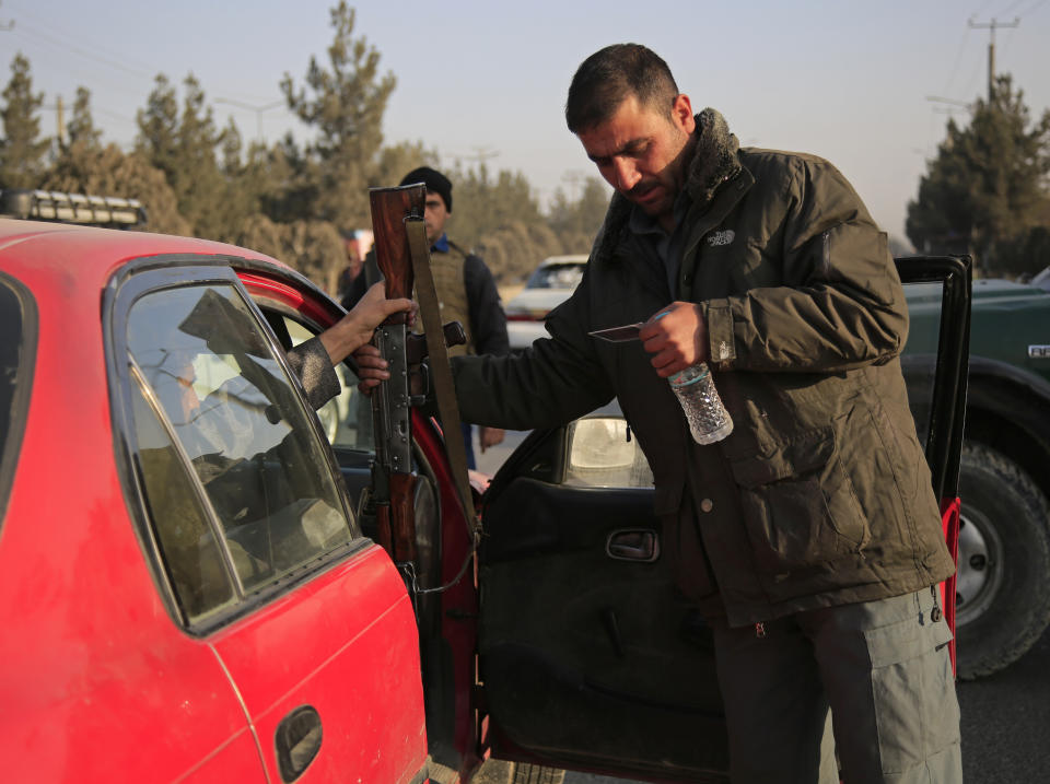 An Afghan policeman checks the documentation of a gun owner at a temporary checkpoint in Kabul, Afghanistan, Monday, Jan.18, 2021. Afghanistan is supposed to be moving toward peace after decades of war, but to the people of the capital Kabul, turmoil only seems to be getting worse. In broad daylight, armed men rob stores, people in parks and cars stuck in traffic. (AP Photo/Mariam Zuhaib)