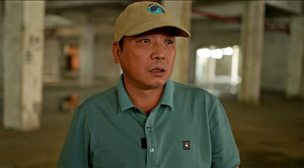 Ren Wenbing stands inside empty factory