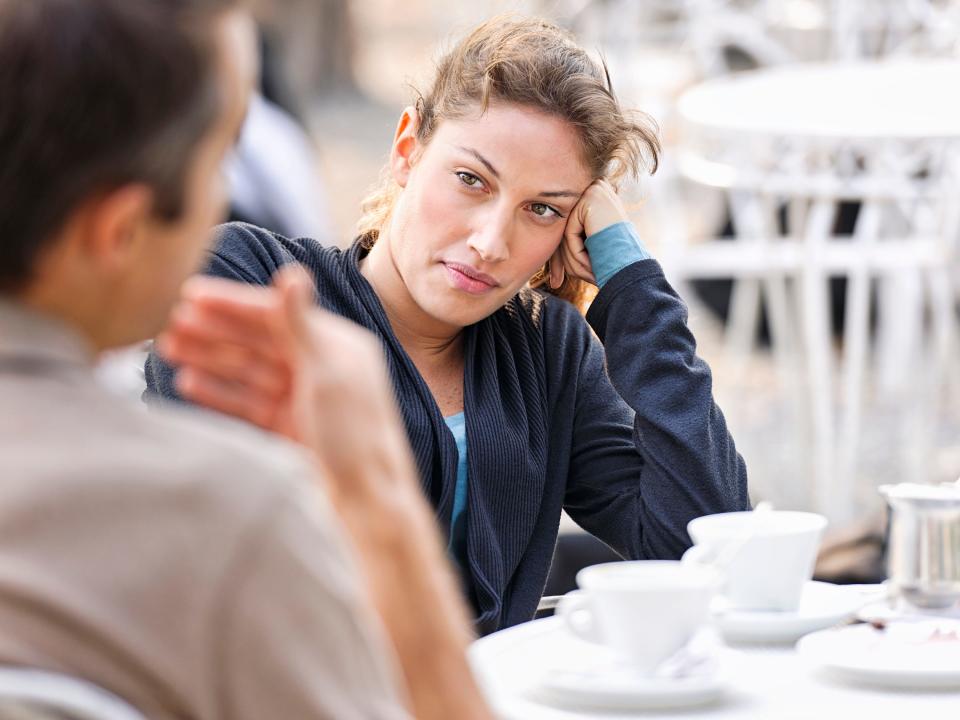 A couple on a coffee date, with one person looking skeptically at their partner.