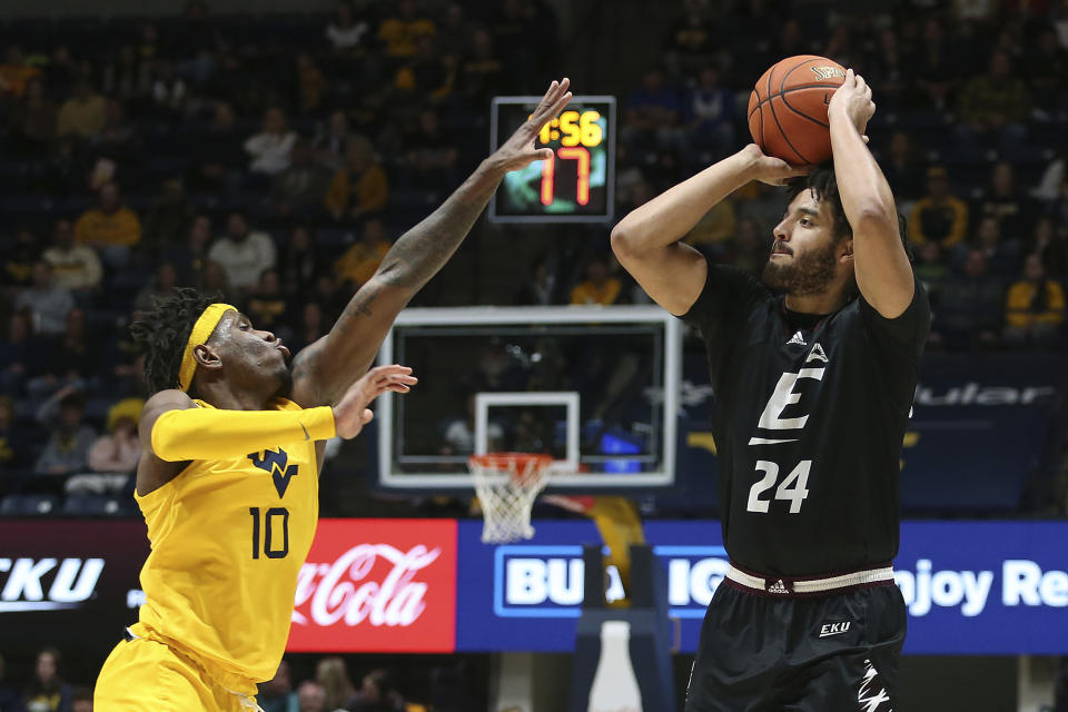 Eastern Kentucky forward Michael Moreno (24) shoots while defended by West Virginia guard Malik Curry (10) during the first half of an NCAA college basketball game in Morgantown, W.Va., Friday, Nov. 26, 2021. (AP Photo/Kathleen Batten)