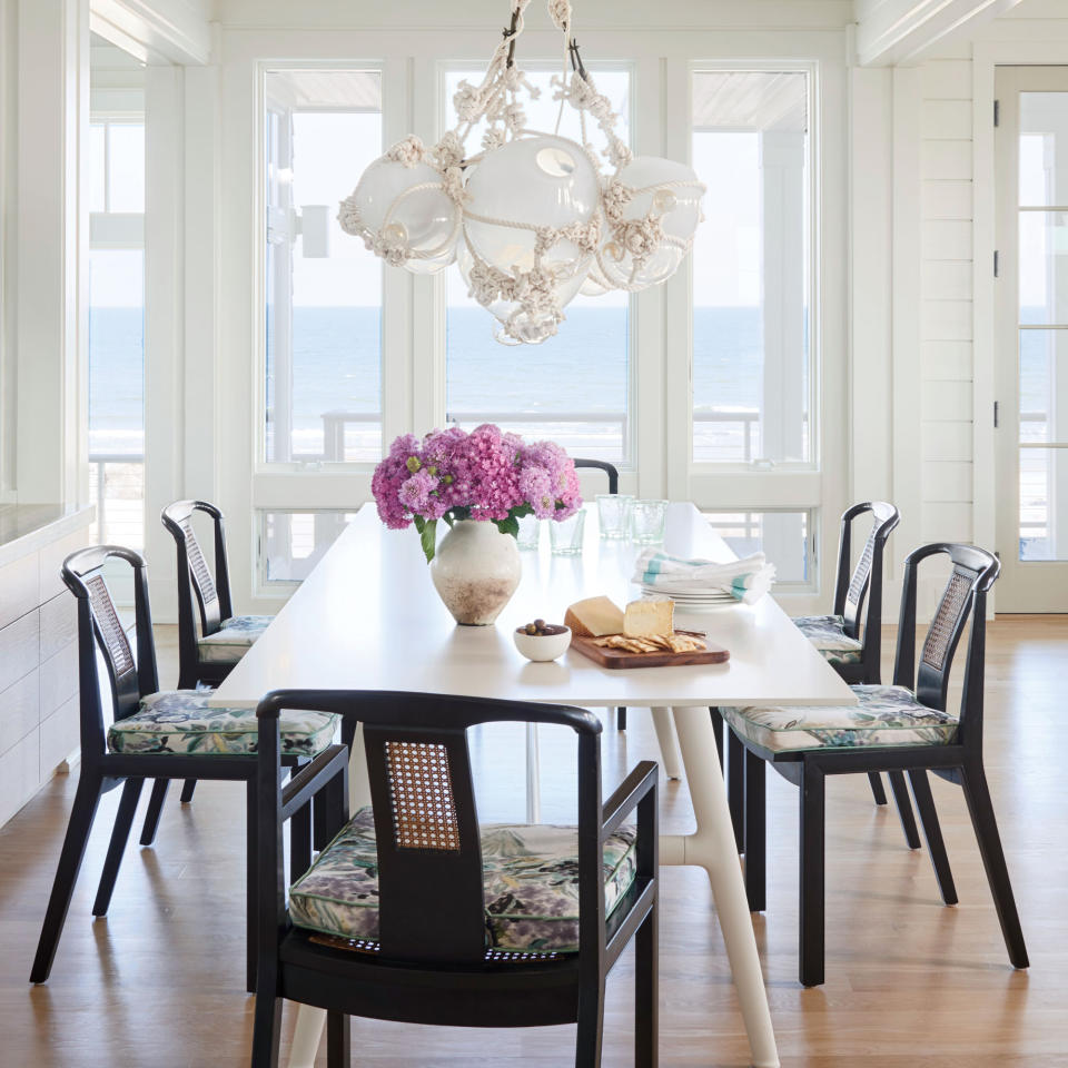 <p>A predominantly white color palette gets its kicks from ebony chairs with cushions upholstered in jewel-tone florals. A sculptural glass-float chandelier by Lindsey Adelman brings in depth and texture without adding competing colors or patterns. </p> <p><strong>Idea Spotlight</strong></p> <p>Maintain a low profile. In this Figure Eight Island, North Carolina, dining room, vintage splat-back chairs and a leggy, modern table keep all eyes on the ocean views.</p>