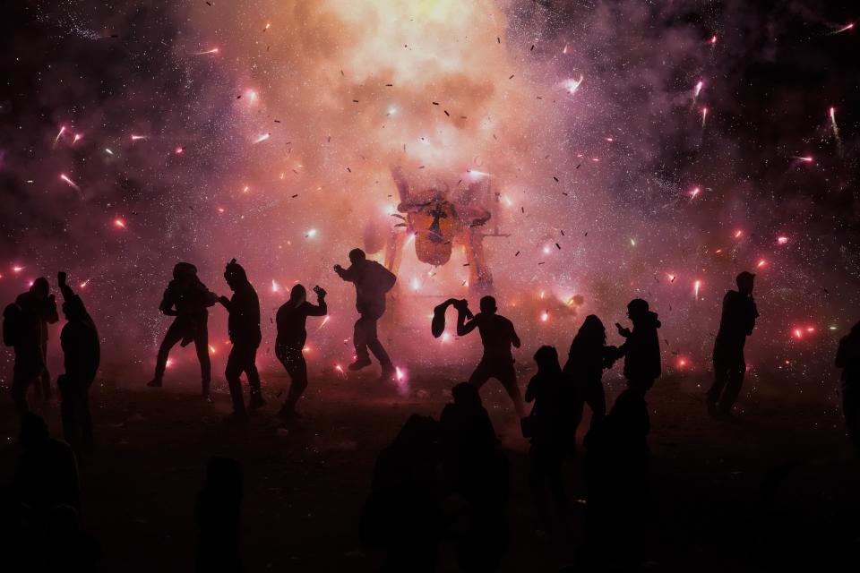 People dance and dodge a giant paper-mache bull stuffed with fireworks as roman candles and bottle rockets shower them with sparks, during the annual festival honoring Saint John of God, in Tultepec, Mexico, Friday, March 8, 2024. The celebration, now its 35th year, pays homage to the patron saint of the poor and sick, St. John of God, who the fireworks' producers view as a protective figure. (AP Photo/Marco Ugarte)