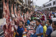 A butcher serves customers during 'Meugang', a local tradition where people shop for meat one day prior to the Eid al Fitr to be cooked and served during the holiday that marks the end of the holy fasting month of Ramadan, amid concerns of the new coronavirus outbreak, at Geudong market in North Aceh, Indonesia, Saturday, May 23, 2020. Indonesia has seen a surge in coronavirus infections ahead of Sunday's celebrations marking the end of Ramadan, raising questions about the commitment to the virus fight from both the government and the public. (AP Photo/Zik Maulana)