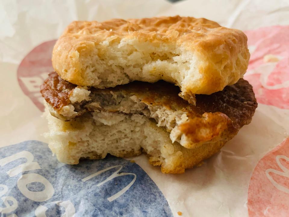 McDonald's sausage biscuit with bite taken out of it on white wrapper