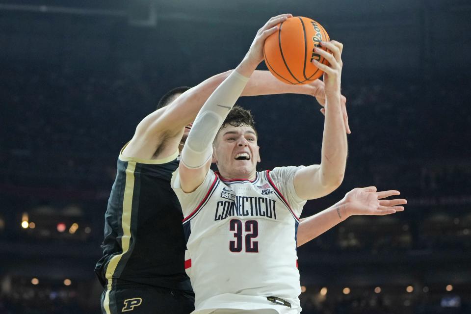 Connecticut Huskies center Donovan Clingan (32) grabs a rebound in front of Purdue Boilermakers center Zach Edey during the 2024 NCAA championship game.