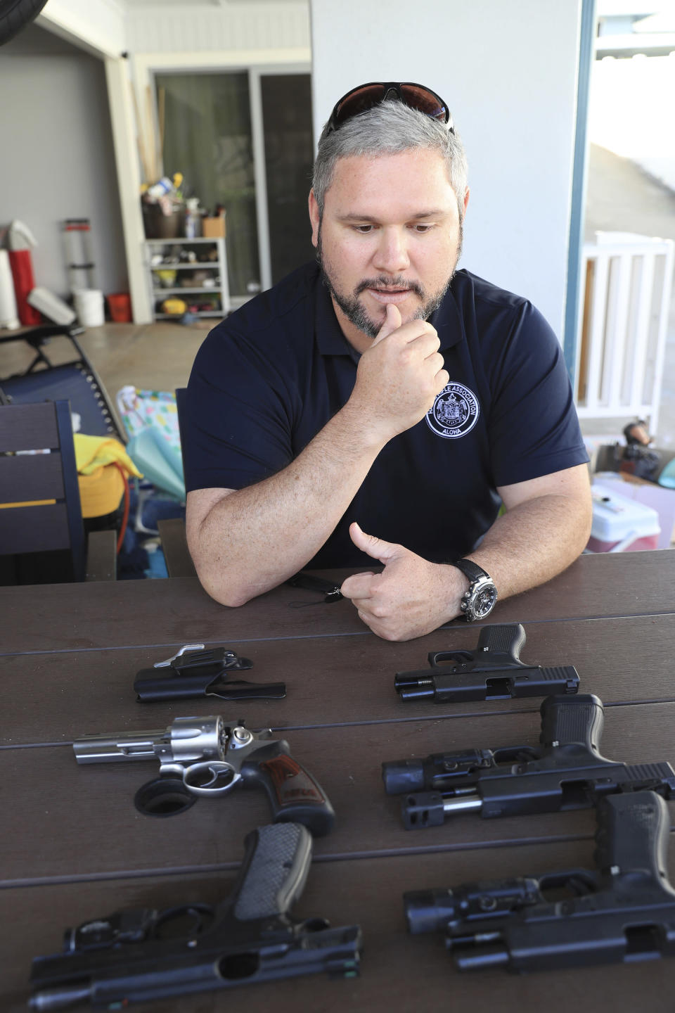 While overlooking several of his personal handguns, Kainoa Kaku, president of the Hawaii Rifle Association, discusses the recent U.S. Supreme Court Ruling while at his home, Thursday, June, 23, 2022, in Honolulu. (AP Photo/Marco Garcia)