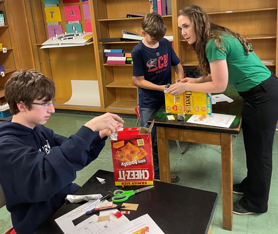 Utica Middle School science teacher Bethany Watson helps eighth grader C.J. Melancon (left) and sixth grader Cody Baker with their CD spectrometer project last week in her classroom.