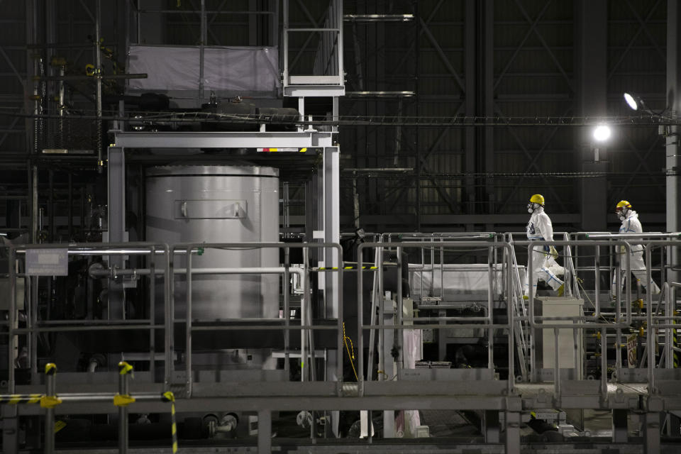 FILE - In this Feb. 12, 2020, photo, two workers wearing hazmat suits work at a water treatment facility at the Fukushima Dai-ichi nuclear power plant in Okuma, Fukushima prefecture, northeastern Japan. The head of the wrecked Fukushima nuclear plant said Tuesday, March 2, 2021 there's no need to extend the current target to finish its decommissioning in 30-40 years despite uncertainties about melted fuel inside the plant's three reactors. (AP Photo/Jae C. Hong, File)