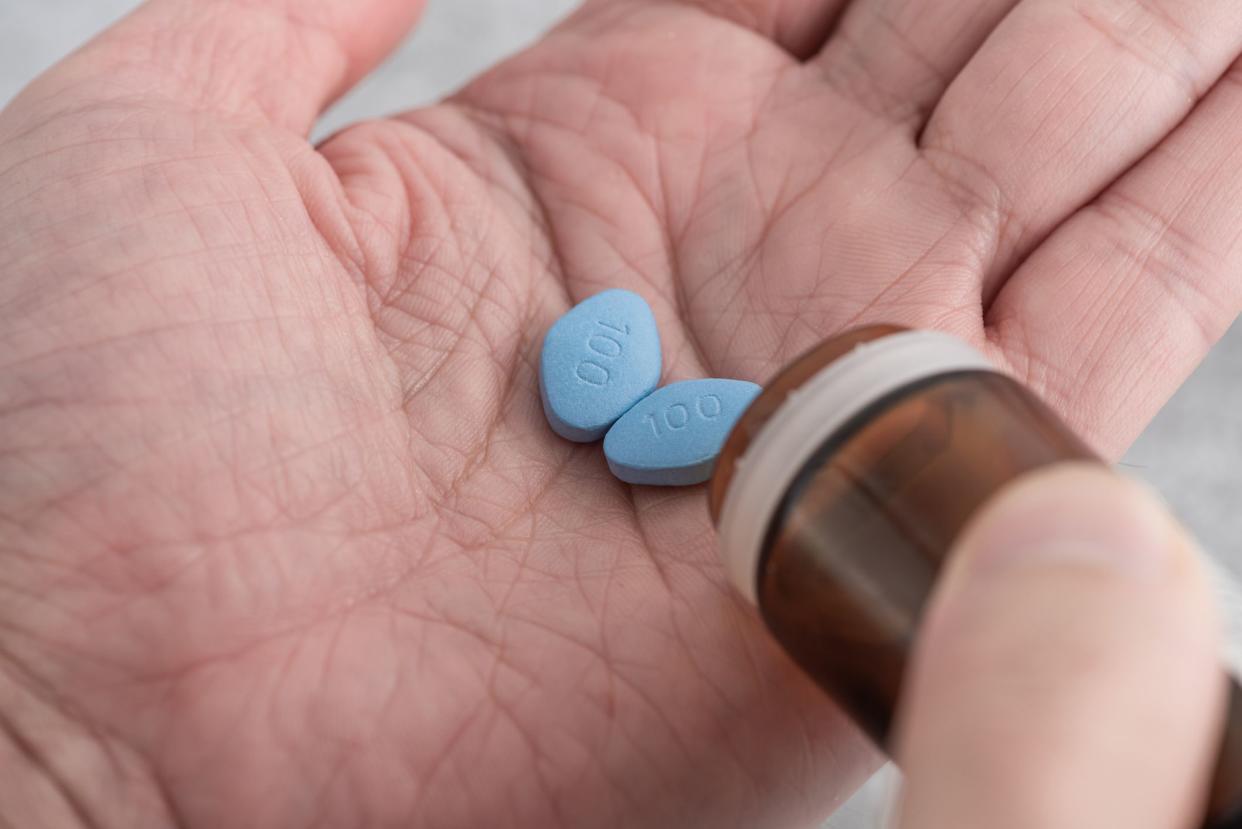 Man takes blue pills in hand. Medicine concept of viagra, medication for erection, treatment of erectile dysfunction. Men health. Close up