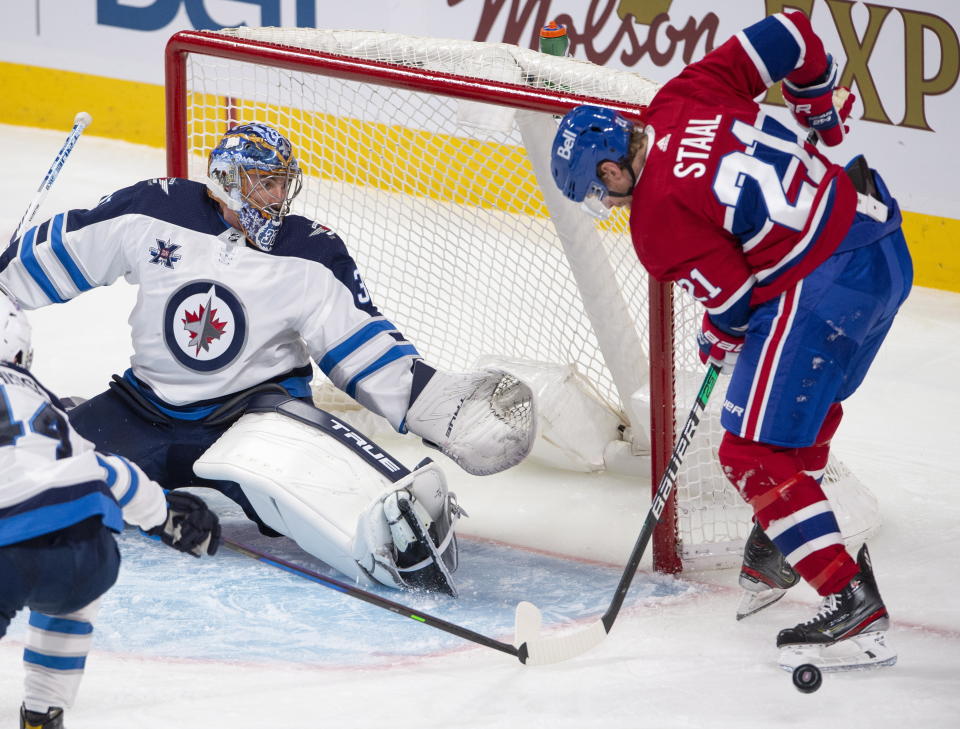 Winnipeg Jets goaltender Connor Hellebuyck (37) makes a save as Montreal Canadiens' Eric Stall looks for the rebound during the second period of an NHL hockey game, Thursday, April 8, 2021 in Montreal. (Ryan Remiorz/The Canadian Press via AP)