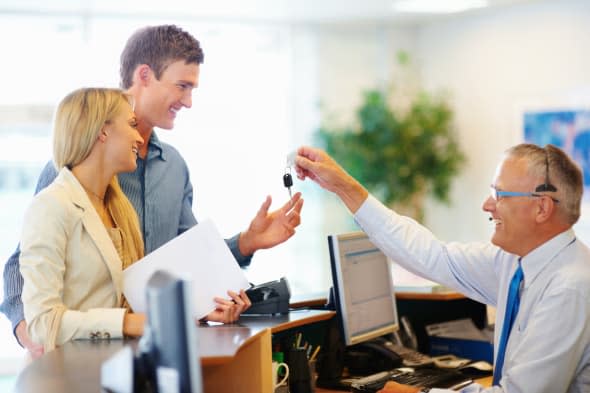 CXDWGB Senior employee handing a smiling couple the key to their car rental Car; hire; rental; couple; vehicle; company; adult;