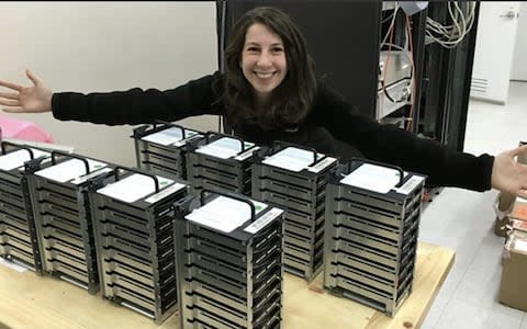 Dr Katie Bouman posing with stacks of hard drives which stored the data from the telescopes - Credit: @MIT_CSAIL/Twitter