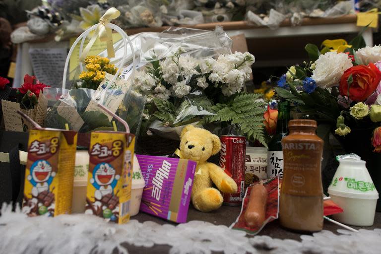 Flowers, drinks, food and a teddy bear sit on a makeshift memorial at the main gate of Danwon high school in Ansan, on April 27, 2014