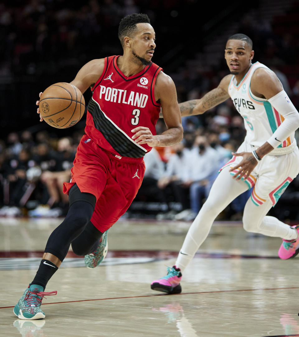 Portland Trail Blazers guard CJ McCollum, left, dribbles past San Antonio Spurs guard Dejounte Murray during the second half of an NBA basketball game in Portland, Ore., Thursday, Dec. 2, 2021. (AP Photo/Craig Mitchelldyer)