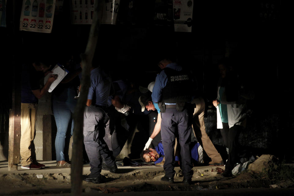 The body of a man lies in the middle of a street as police and forensic workers inspect the crime scene in the Rivera Hernandez neighborhood of San Pedro Sula, Honduras, on Nov. 30, 2019. (AP Photo/Moises Castillo)