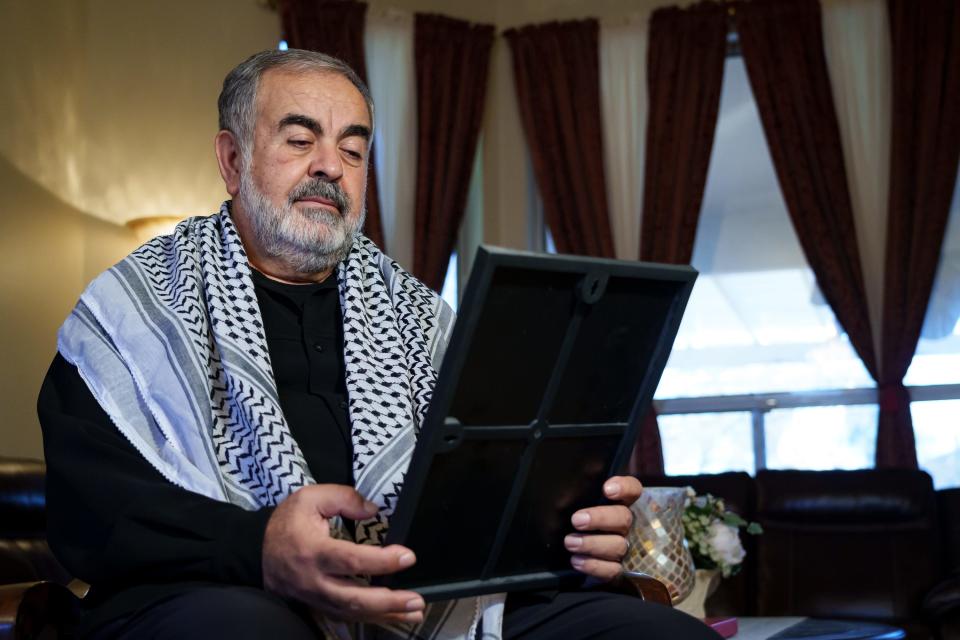 Palestinian American Mohamed El-Sharkawy poses for a portrait in his home on Dec. 21, 2023, in Phoenix. He looks down at a framed photograph of his four nieces who are currently in Gaza with their homes destroyed.