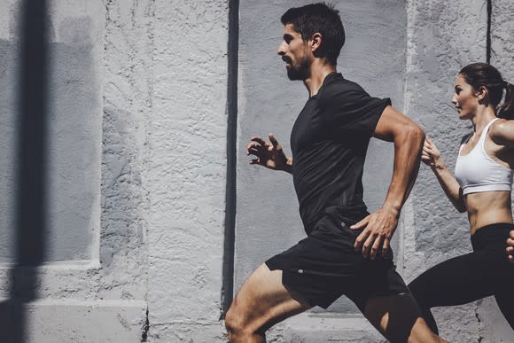 A man and woman running while wearing Lululemon apparel.