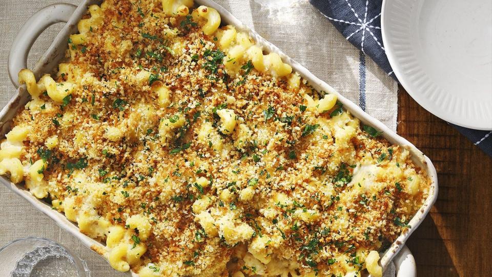 cauliflower mac and cheese in a white rectangle baking dish with some in a bowl on the side