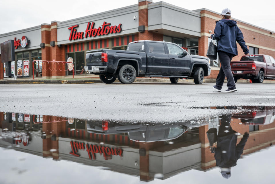 A Tim Hortons store is reflected in a rain puddle as business goes on despite a wildfire risk in Fort McMurray, Alta., Thursday, May 16, 2024.THE CANADIAN PRESS/Jeff McIntosh