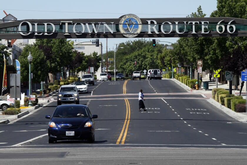 Khan, Irfan –– B582213710Z.1 VICTORVILLE, CA, July 03, 2012 ––– A pedestrian crosses 7th. Street in old town area of Victorville. City is teetering on the brink of financial ruin due to some bad financial investments. Green Tree golf course, where the city dumped a ton of money into the club house, the old airbase, the old plane boneyard and an abandoned house that city paid $375,000 are some of many bad financial decisions that put into trouble.(Irfan Khan/Los Angeles Times)