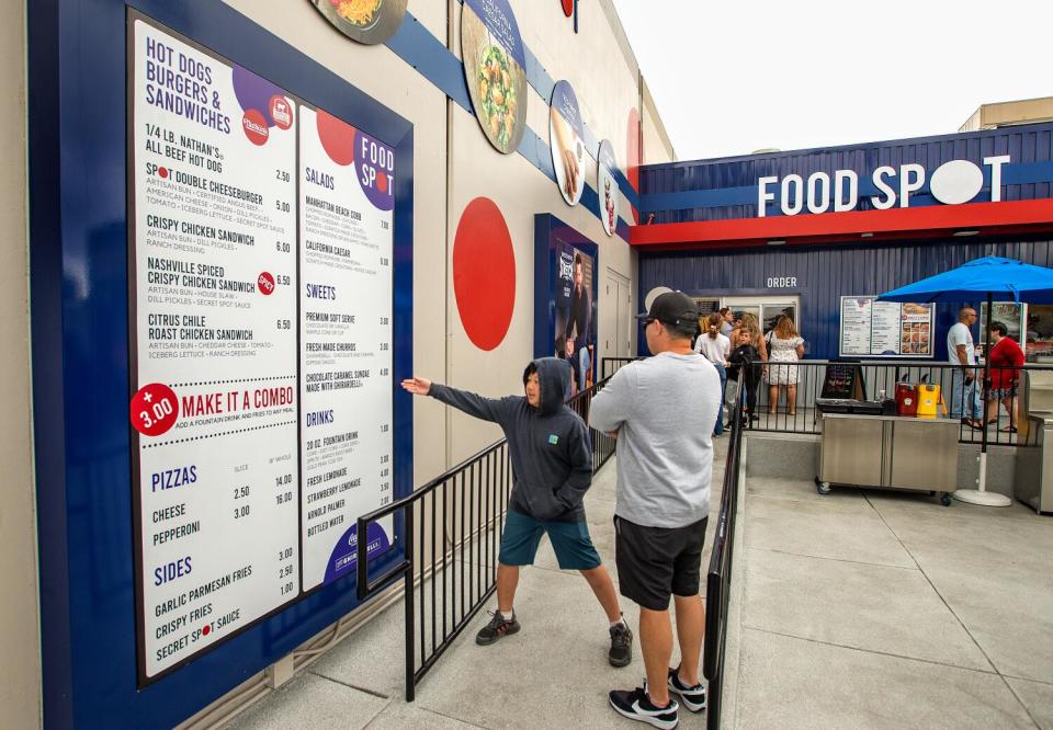 A man and a boy look at a menu on the wall at Food Spot.