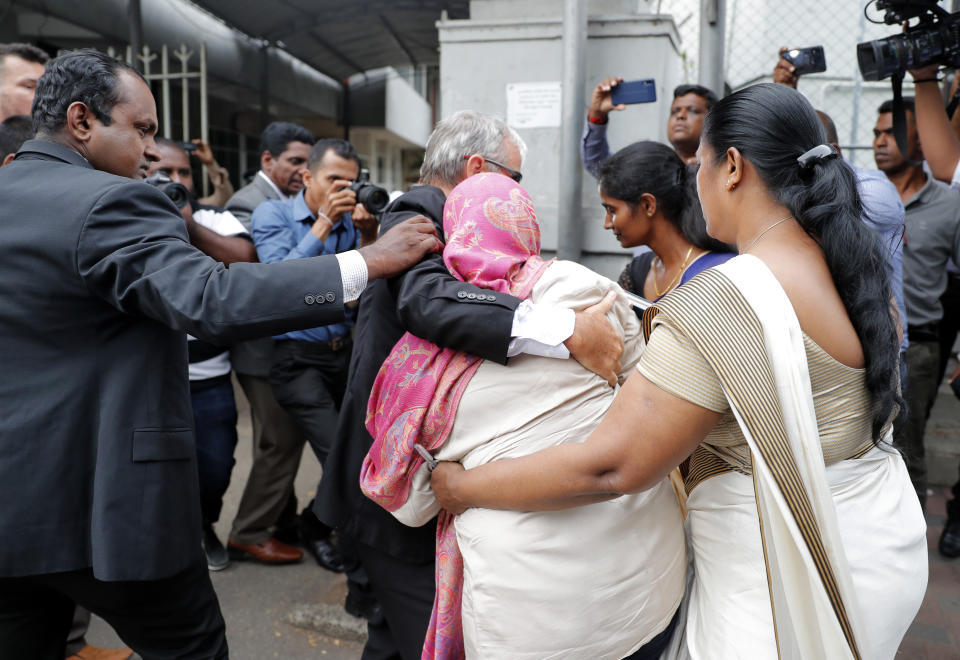 Sri Lankan Swiss embassy worker Garnier Banister Francis, covered in pink shawl, holds on to an unidentified foreign national as Sri Lankan police officers escort her to a magistrate court after her arrest in Colombo, Sri Lanka, Monday, Dec. 16, 2019. (AP Photo/Eranga Jayawardena)
