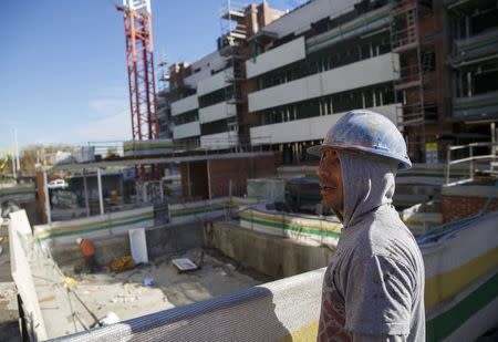 A worker looks over a construction site of a residential block in the Valdebebas neighbourhood in Madrid December 10, 2014. REUTERS/Andrea Comas