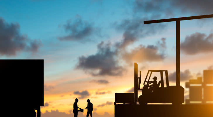 silhouettes of a forklift and driver as well as two workers by a semi truck backdropped by a sunset sky. represents the supply chain