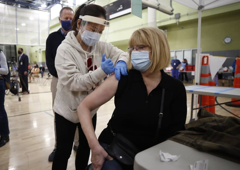 LOS ANGELES, CA - FEBRUARY 17: Pacoima Middle School teacher Abigail Abbott, 65, gets her COVID-19 vaccination from Nurse Practitioner Jiyoun Cho, left, as Los Angeles Unified employees received their first dose of the vaccine Wednesday morning. The Moderna vaccine was administered by Los Angeles Unified school nurses and other licensed healthcare professionals at the Roybal Learning Center, becoming Los Angeles Unified's first school-based vaccination center. Roybal Learning Center on Wednesday, Feb. 17, 2021 in Los Angeles, CA. (Al Seib / Los Angeles Times).