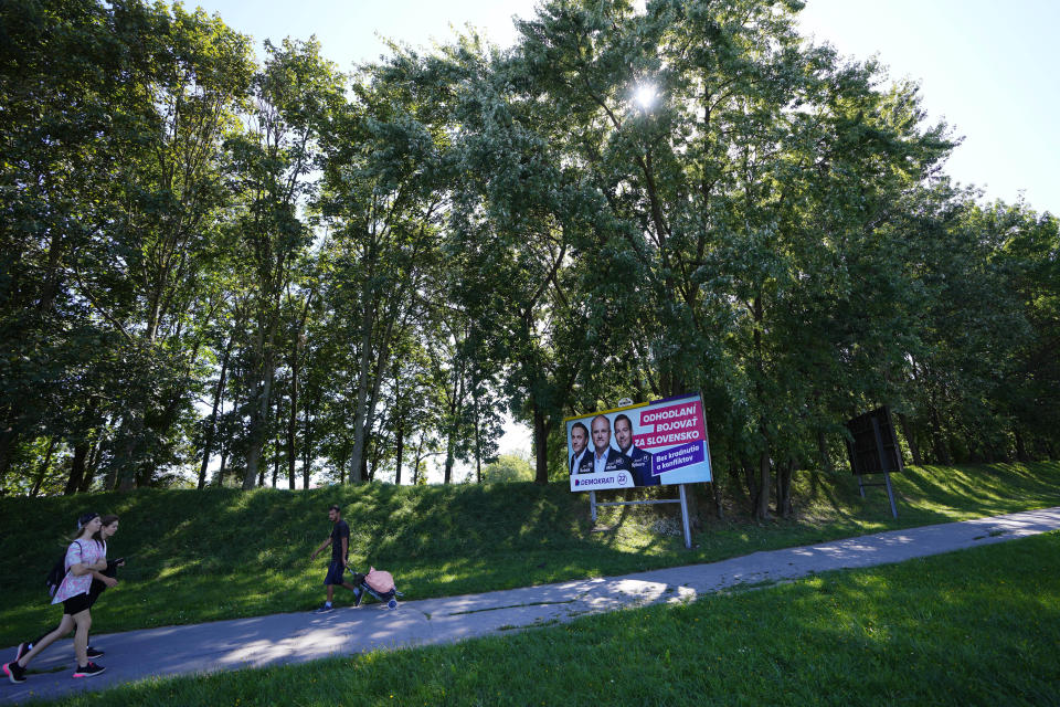 People walk past an election billboard for "Demokrati" (Democrats) movement in Michalovce, Slovakia, Wednesday, Sept. 6, 2023. The billboard reads: 'SaS economic growth for the east'. Slovakia holds early parliamentary elections on Saturday Oct. 30, 2023, with a populist former prime minister Robert Fico and his scandal-tainted party "SMER" (Direction) favored to win after campaigning on a clear pro-Russian and anti-American message. (AP Photo/Petr David Josek)