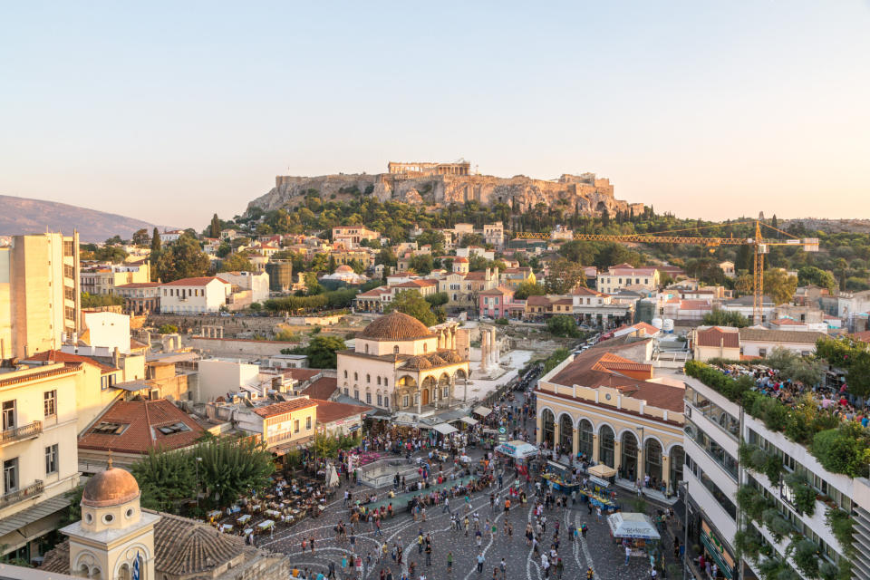 View of Monastiraki square crowded with tourists and the Acropolis at sunset.