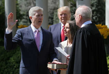 FILE PHOTO: Judge Neil Gorsuch (L) is sworn in as an associate justice of the Supreme Court by Supreme Court Associate Justice Anthony Kennedy (R) , as U.S. President Donald J. Trump (C) watches with Louise Gorsuch in the Rose Garden of the White House in Washington, U.S. on April 10, 2017. REUTERS/Carlos Barria/File Photo