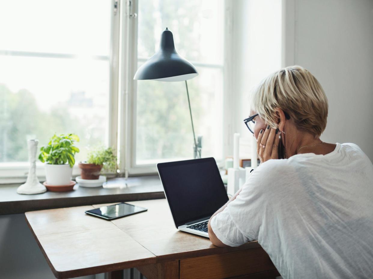 Woman working on laptop on desk buy window.