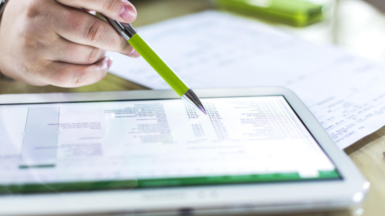 person recording financial transactions on tablet