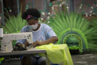 Carmen, una trabajadora de la escuela de samba Vila Isabel, cose trajes desechables para trabajadores sanitarios durante la pandemia del coronavirus, en Río de Janeiro, Brasil, el 7 de abril de 2020. Las escuelas de samba de Río de Janeiro suelen pasar el año cosiendo frenéticamente los disfraces para el impresionante Carnaval de la ciudad. Ahora, esos ágiles dedos trabajan para proteger vidas, elaborando trajes de protección para los empleados de salud que enfrentan una oleada de pacientes con coronavirus. (AP Foto/Silvia Izquierdo)